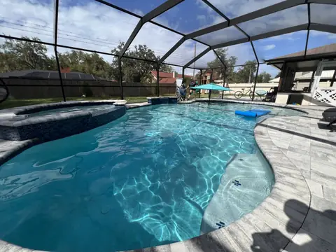 Freeform pool under a screen enclosure with a covered lanai