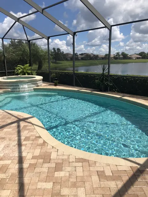Kidney-shaped pool under a screen with a lake behind it