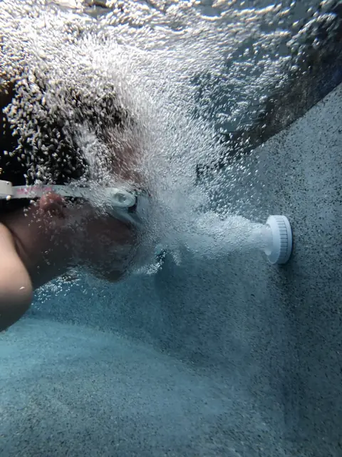 Underwater view of bubbles streaming from a pool return jet